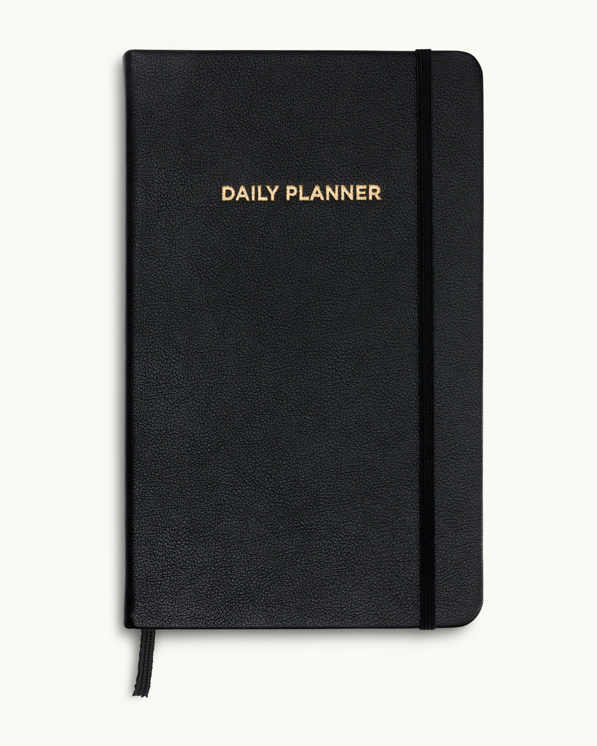 Black daily planner with gold-embossed title on textured vegan leather cover.