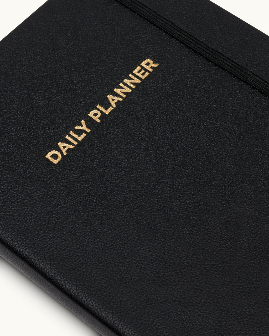 Close-up of black planner cover with gold-embossed “Daily Planner” text.