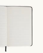 Right page of the open black Matine Daily Planner showing the lined “Notes” page with rounded corners and ribbon bookmark visible.