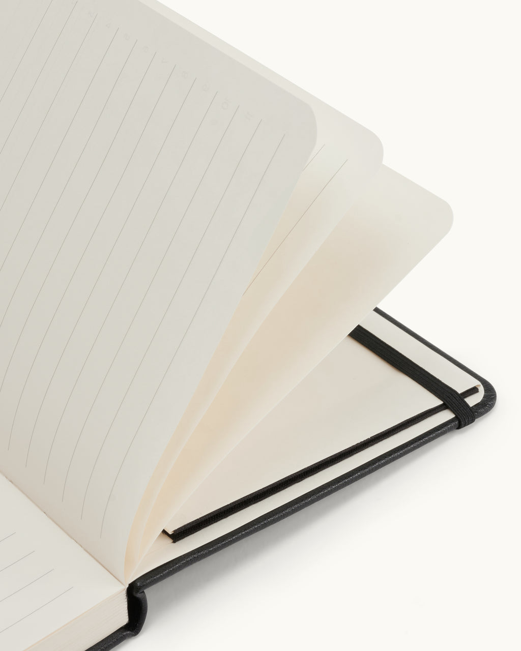 Close-up of the open black Matine Daily Planner showing lined pages, rounded corners and black elastic band.