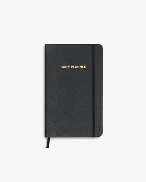Schwarzer Daily Planner mit goldener Prägung auf dem Cover, frontal aufgenommen.