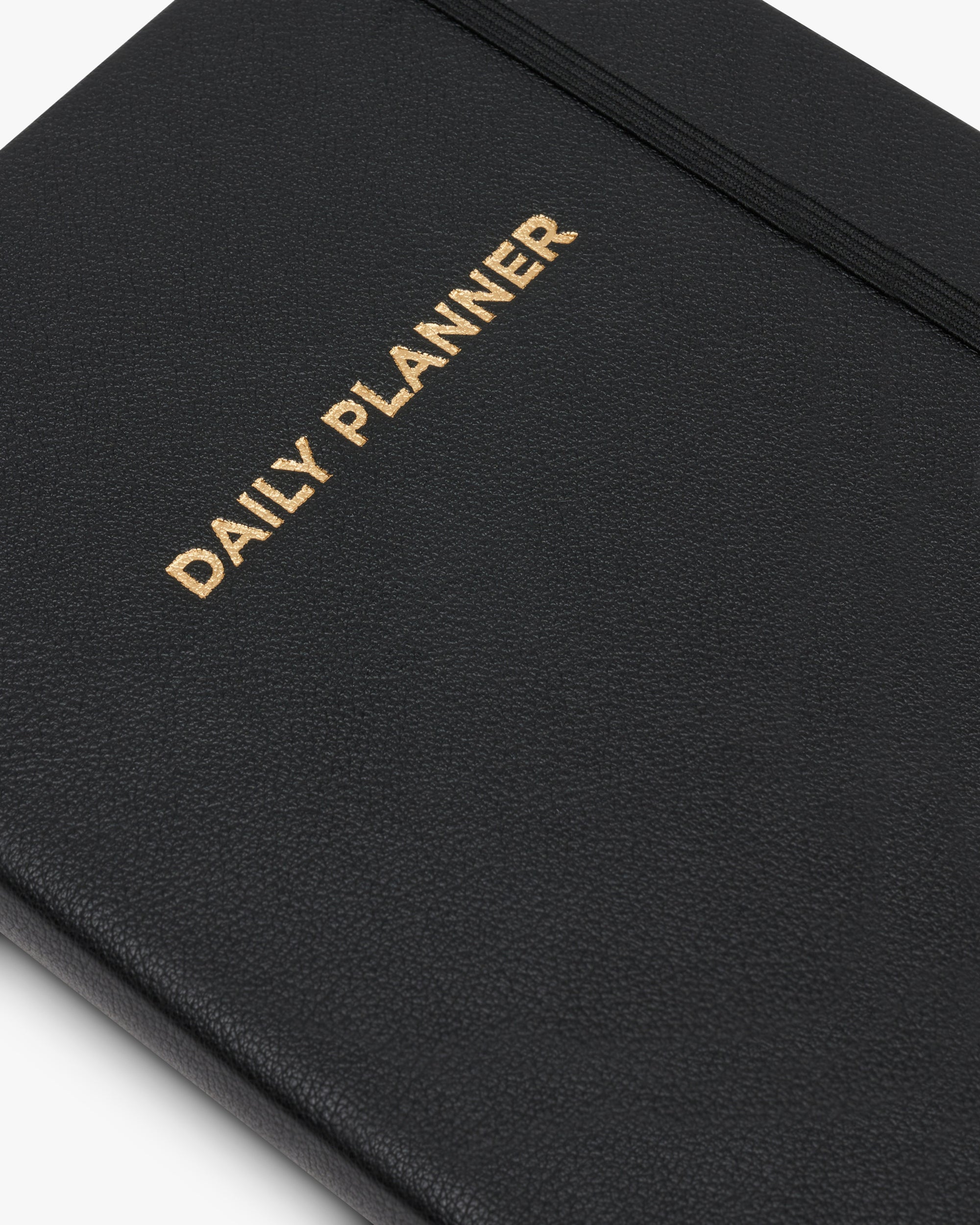 Nahaufnahme des schwarzen Daily Planners mit goldgeprägtem Titel auf dem Cover.